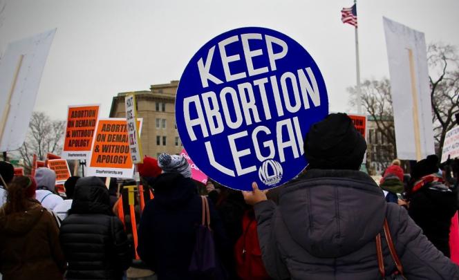 A protester holding a circular sign says "Keep Abortion Legal"