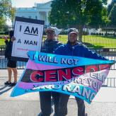 Two protesters hold signs at a rally for trans rights