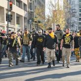 A group of men, in Proud Boys gear walking on a street.