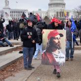 A woman wearing a red hat, holding a paining of Jesus wearing a Make America Great Again hat.