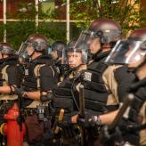 State police standing in line holding batons.