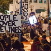 A protester holding a sign that reads "people over pipelines"