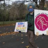 A person at a protest holding a sign that says DeGrow the North and Decolonize the south
