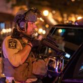A sheriff pointing a gun at a car.