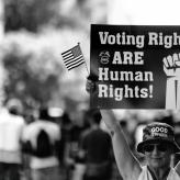 A person holding a banner saying "voting right are human rights!"