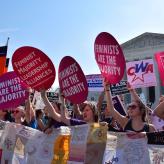 Women holding up signs that say "Feminist majority leadership alliances" in front of the Supreme Court