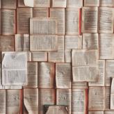Open books laid horizontally across a table with a couple laid vertically over.