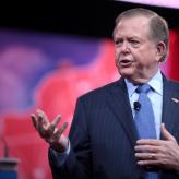 A man in a blue suit, speaking.