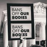 A protestor holding a paper that says "Bans of our bodies"
