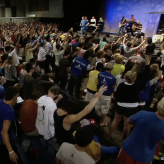 A group of people in a room with their hands raised.