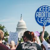 A group of people holding up signs in front of the capitol building