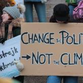 a protester with a sign that says "change the politics not the climate"