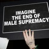 A black sign with the words "imagine the end of male supremacy"