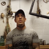 A man in a grey t shirt with hunting memorabilia in the background