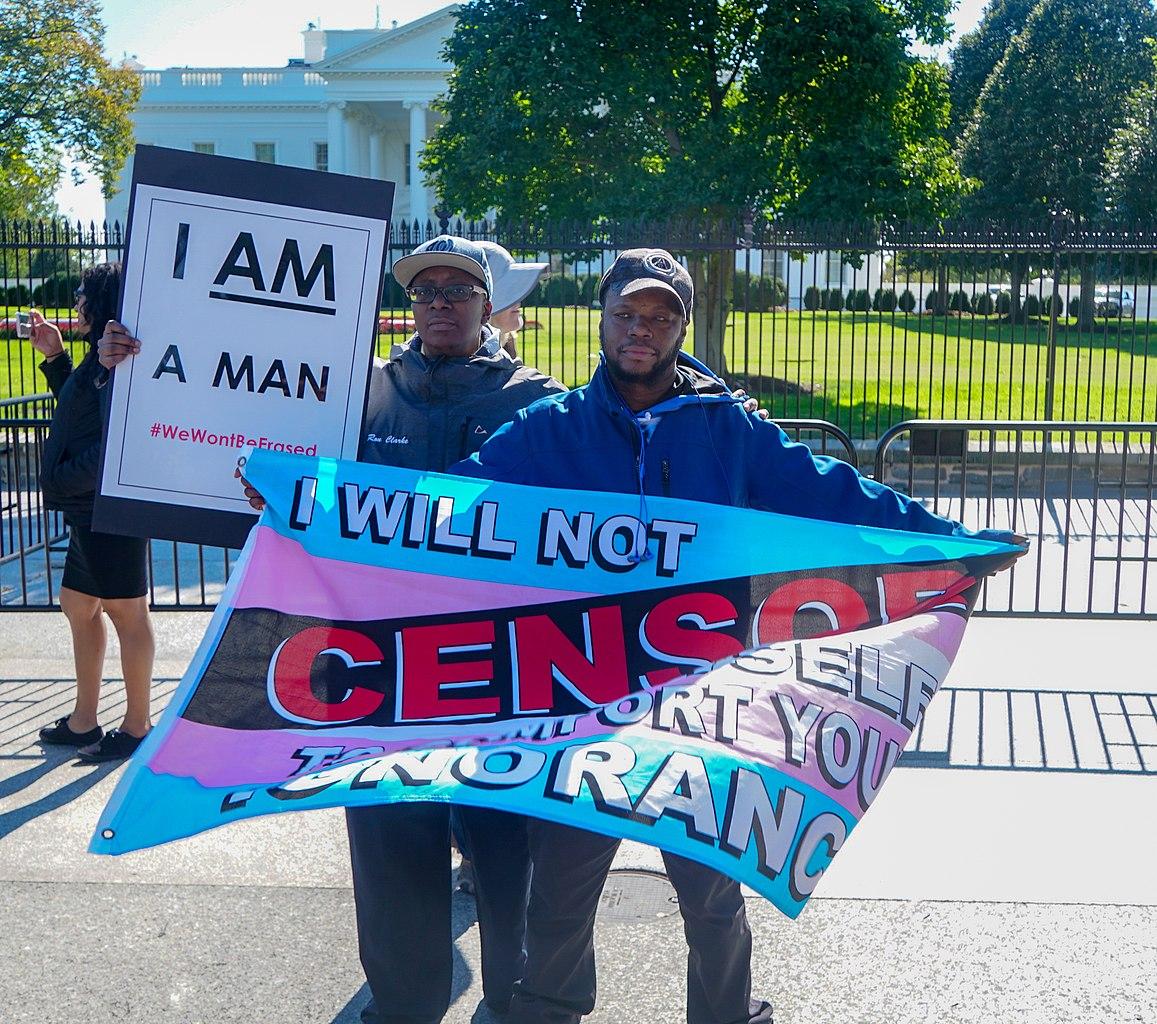 Two protesters hold signs at a rally for trans rights