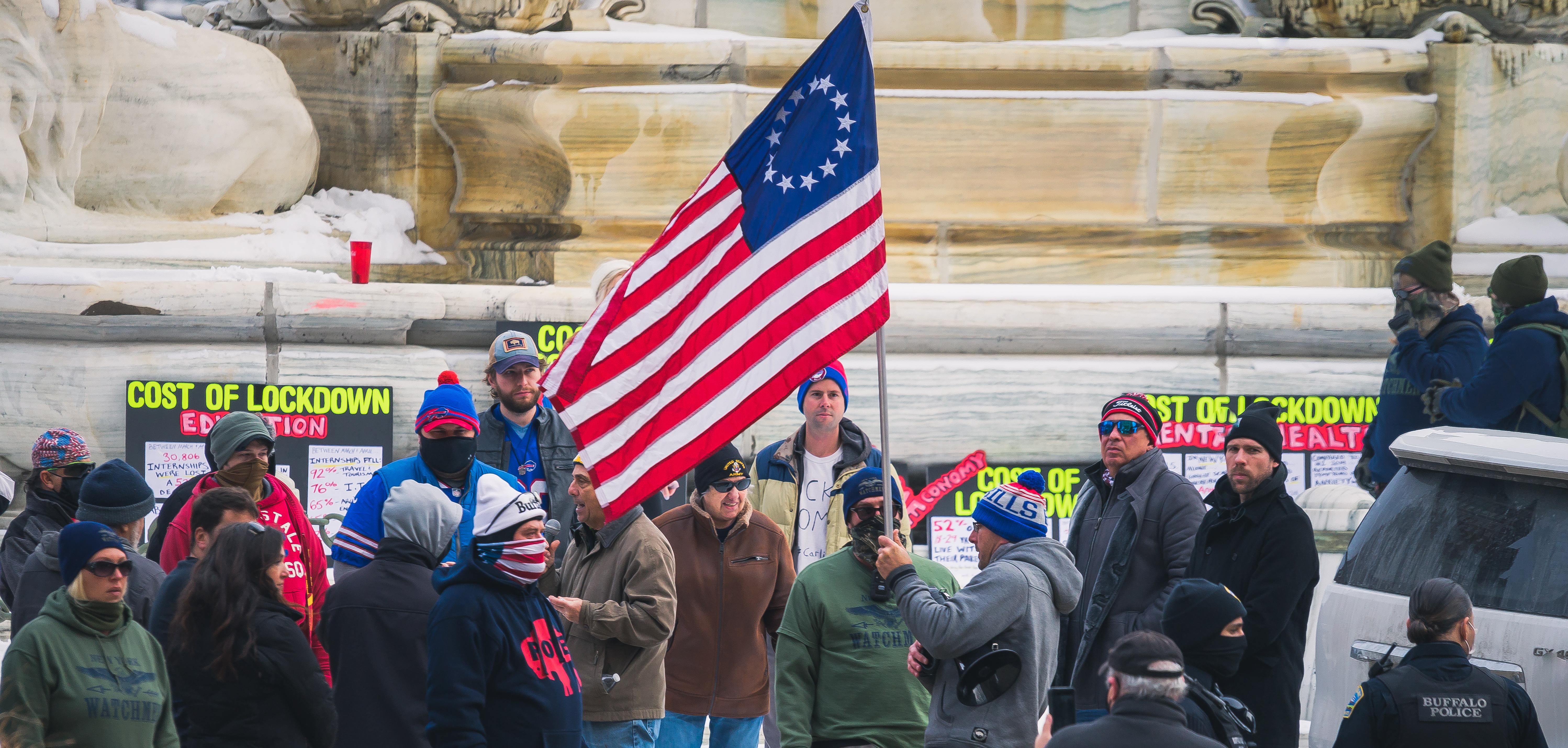 Crowd wearing winter clothes holding colonial American flag