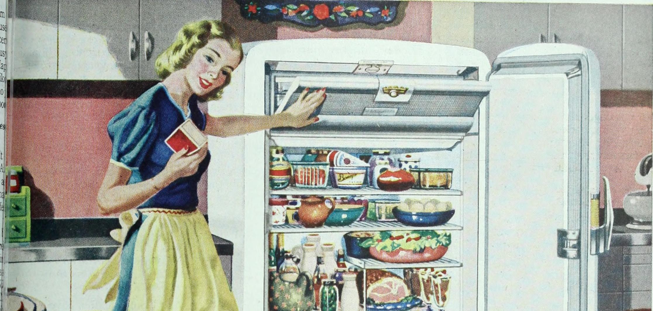 A white woman in a blue dress and a yellow apron, standing in front of an open fridge full of food.