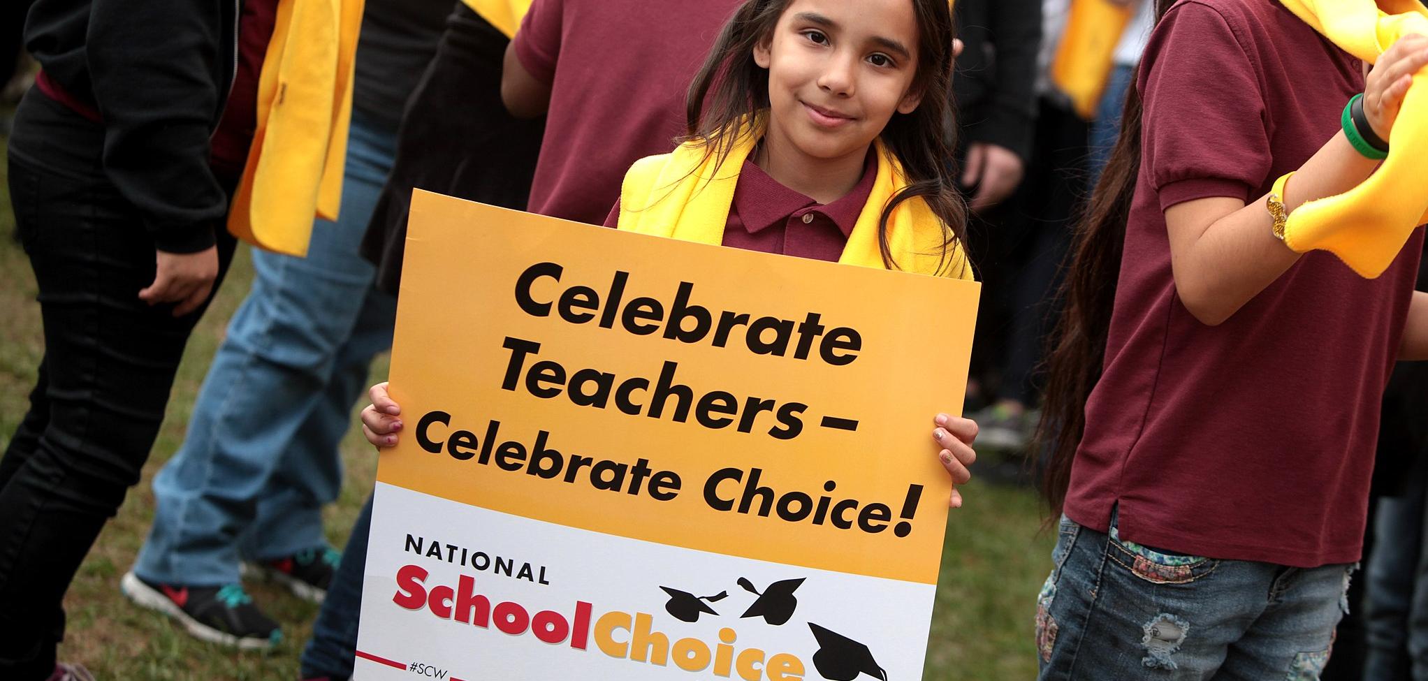 A young girl holding a sign that says Celebrate Teachers - Celebrate Choice! National School Choice Week