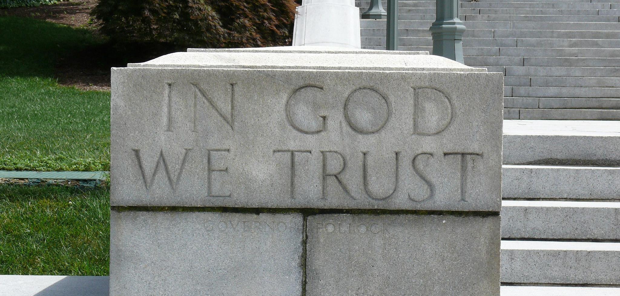 The word In God We Trust engraved in a stone staircase