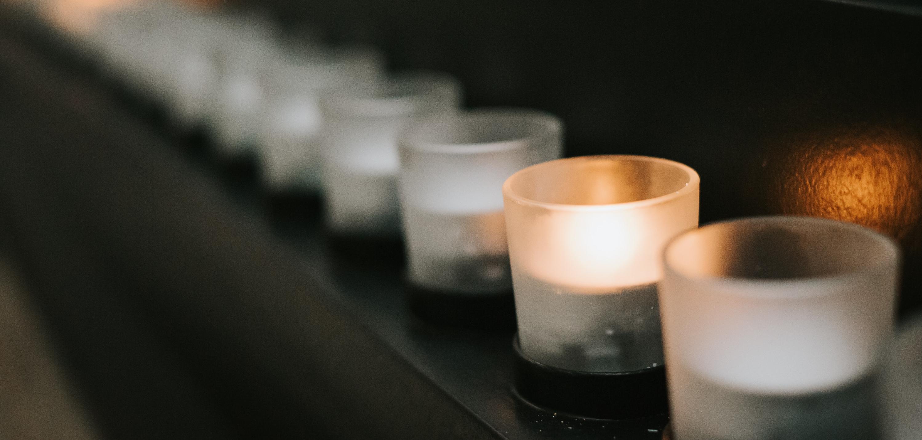 Glass candles in a row, with one of them lit.