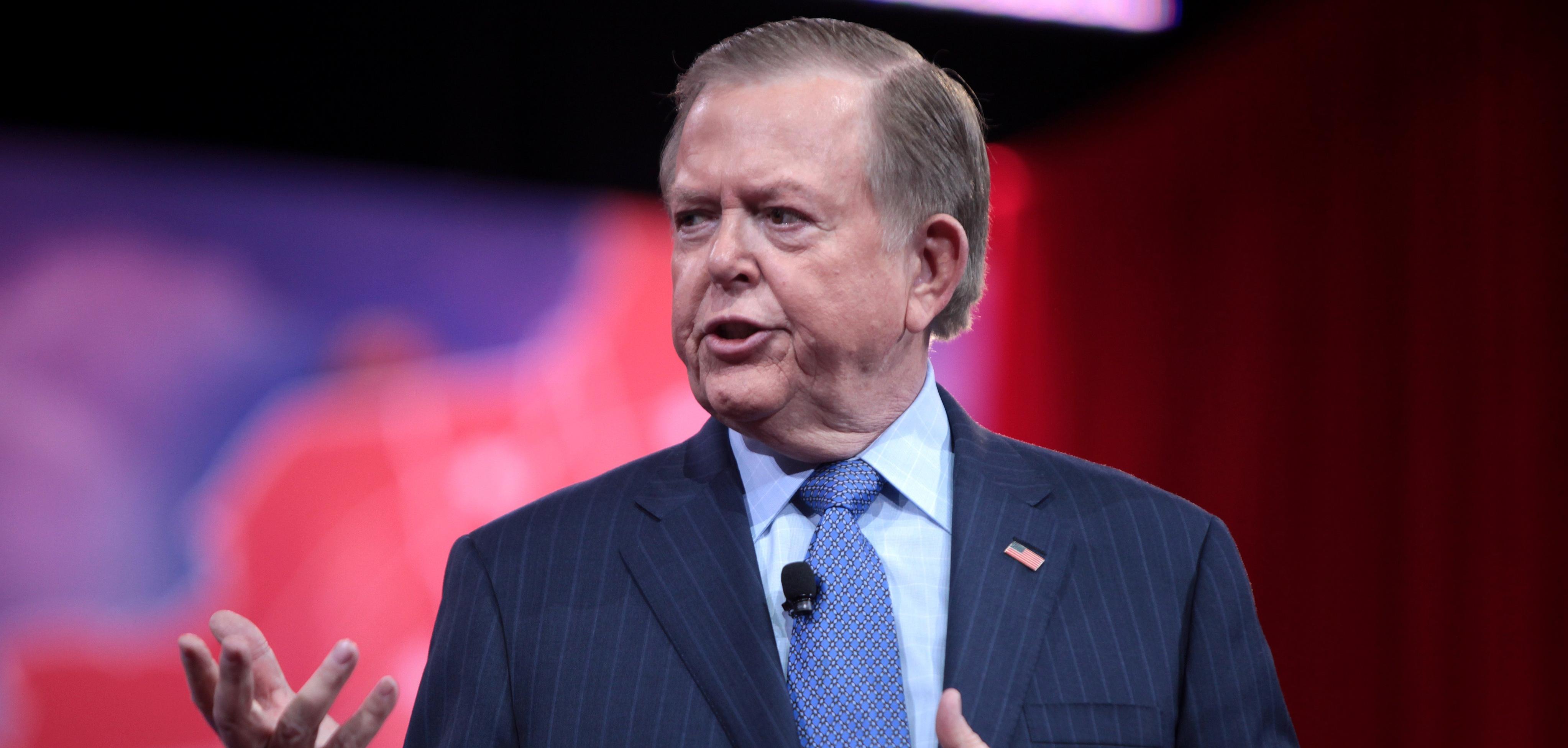 A man in a blue suit, speaking.