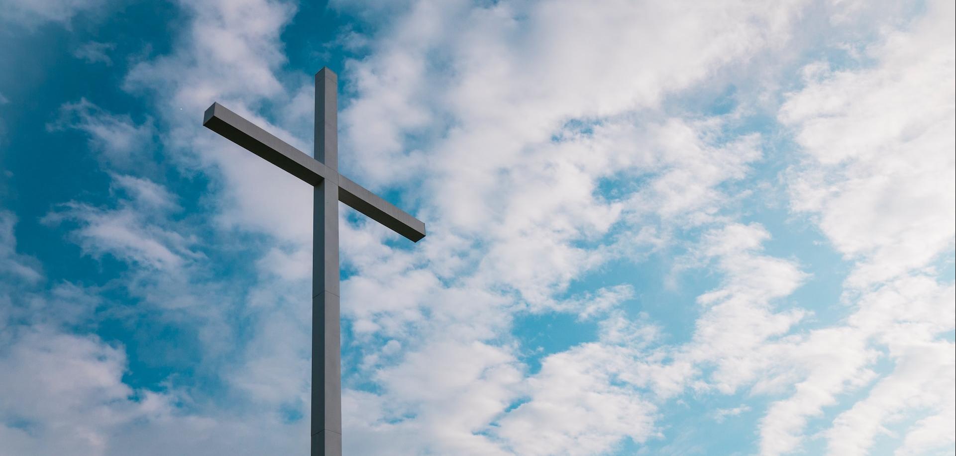 a cross with clouds in the background.