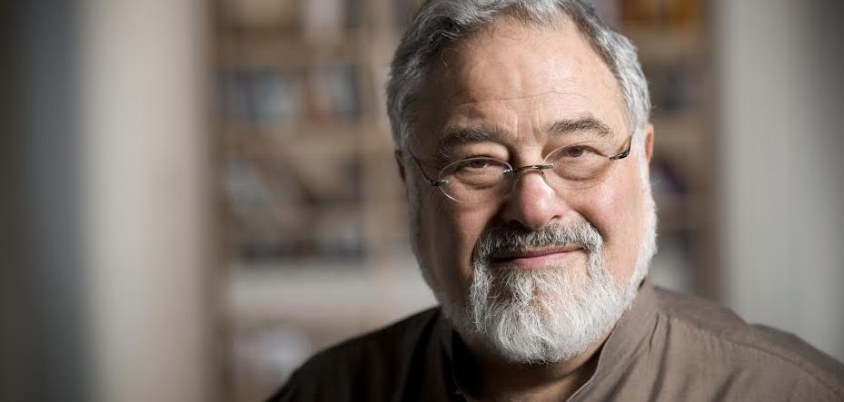 A man with grey hair and grey beard wearing spectacles