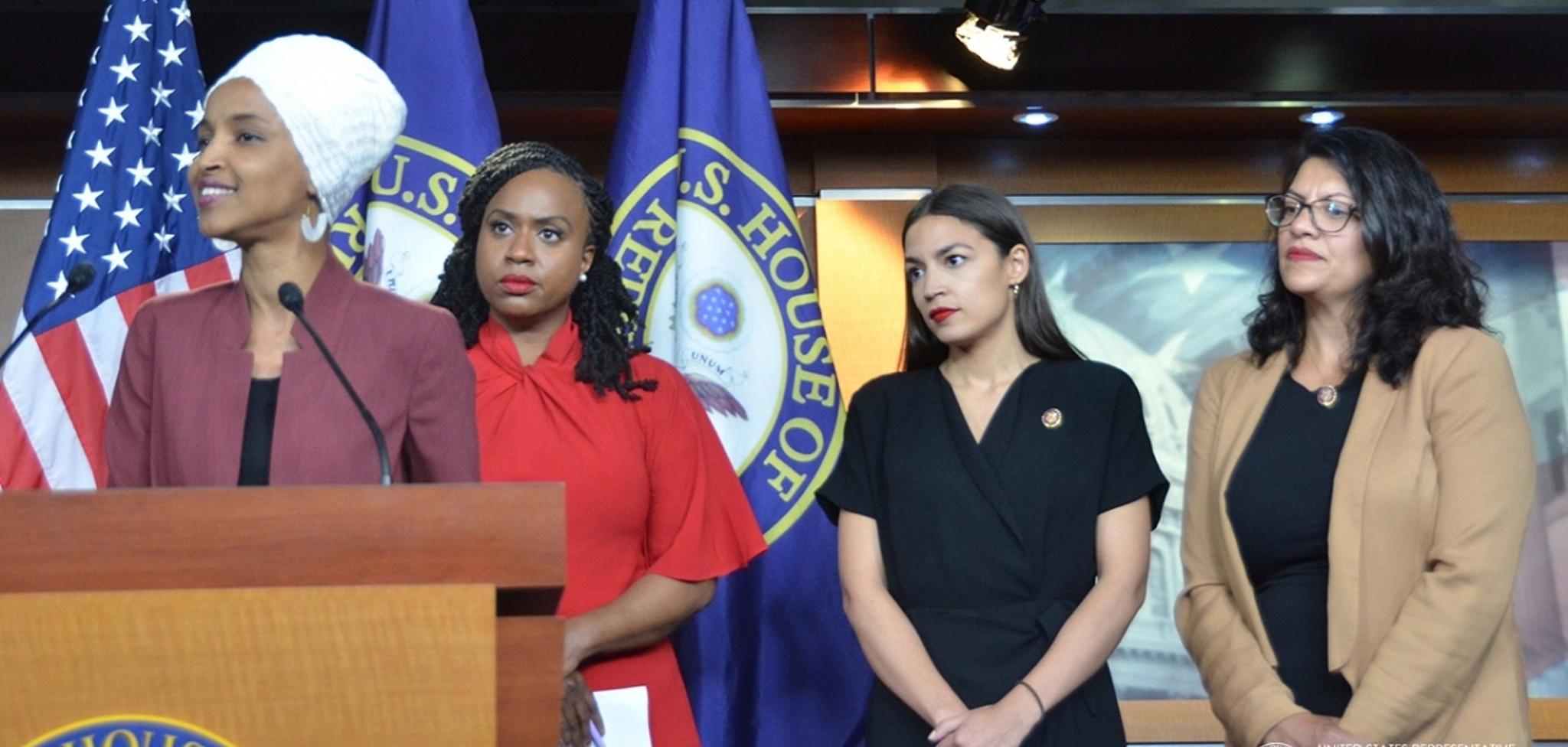 A woman standing in front of a podium with three women behind her.