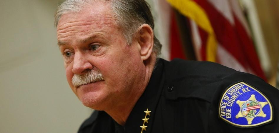 A man with white hair and white mustache in a sheriff's uniform.