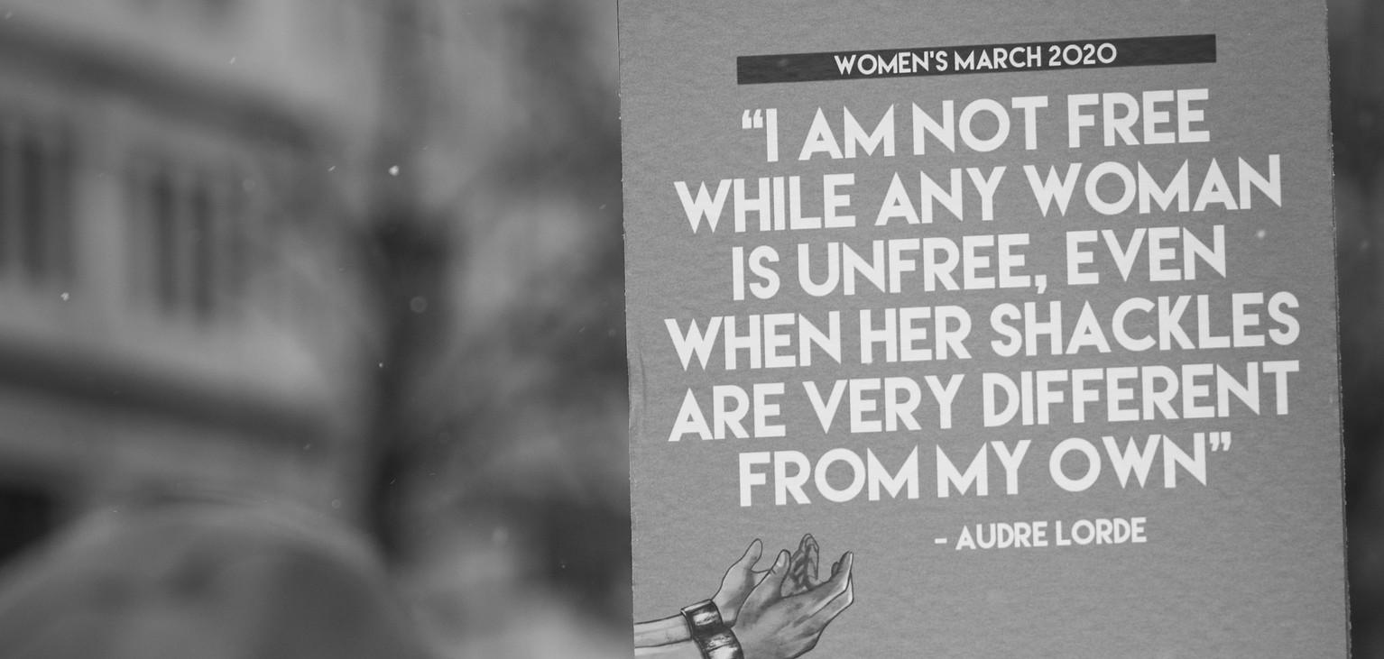 A sign that reads "I am not free while any woman is unfree, even when her shackles are very different from my own" - Audre Lorde